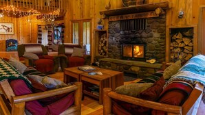 A cozy log cabin interior with a stone fireplace, wooden furniture, and a sign above the fireplace reading "Here Let the Fires of Friendship Burn". - Sun Mountain Ranch Bunkhouse - Near Crater Lake (Fort Klamath)