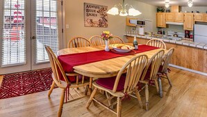 A dining area with a wooden table and chairs, a red rug, and a kitchen in the background. - Oak Tower Townhouse-1.5 Blocks to OSF (Ashland)