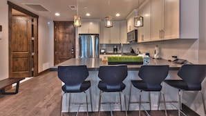 A modern kitchen with a central island, bar stools, stainless steel appliances, and pendant lighting. - Great Location, Chef (Park City)