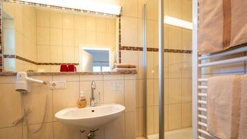 A bathroom with a sink, mirror, and shower area.