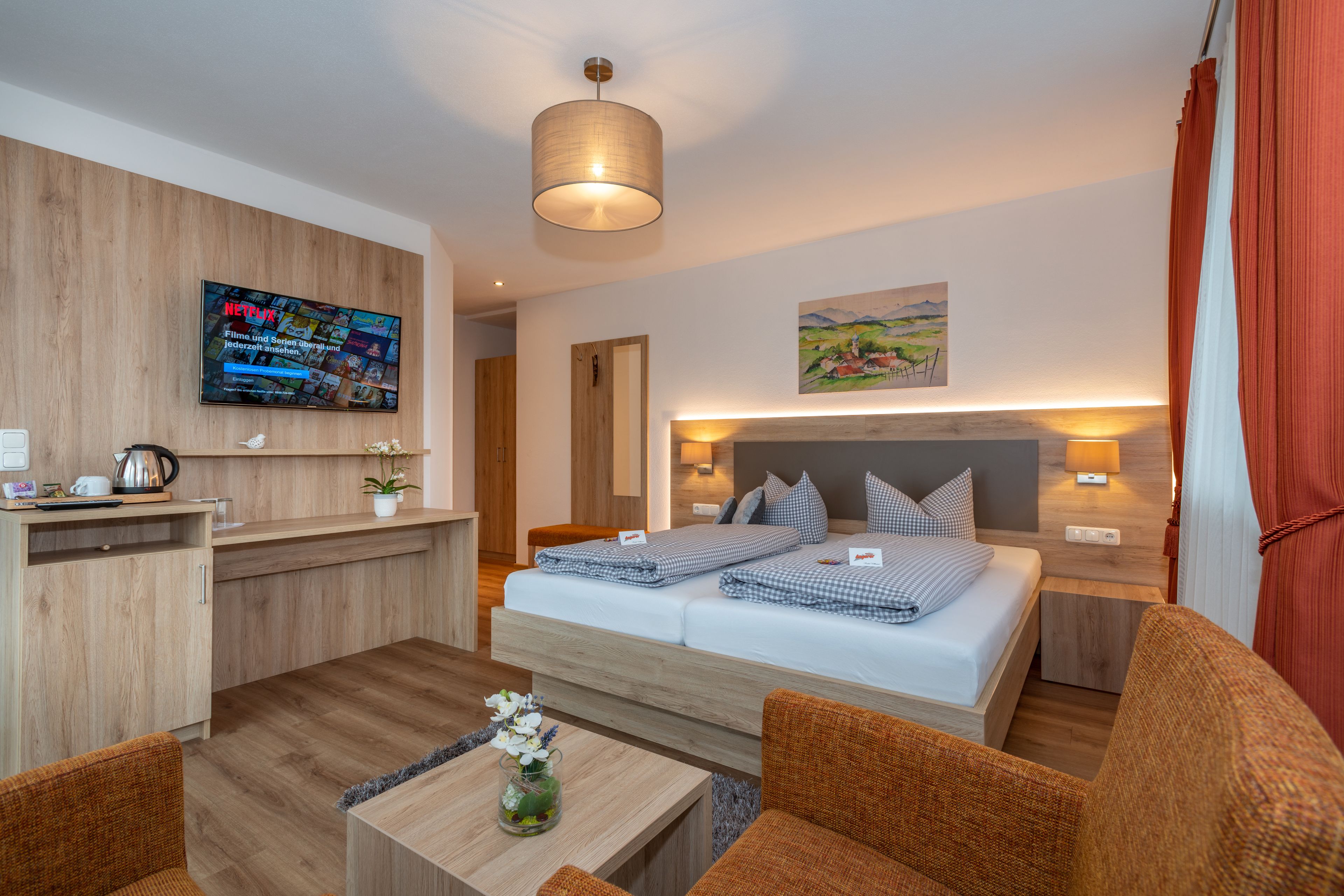 A modern hotel room with a bed, a desk, a TV, and a painting on the wall.