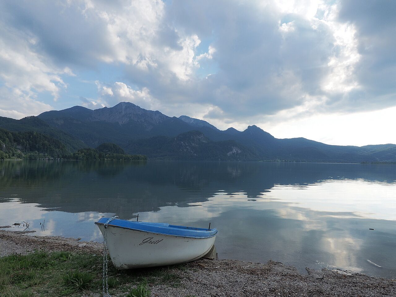 A boat on a calm lake with mountains in the background.