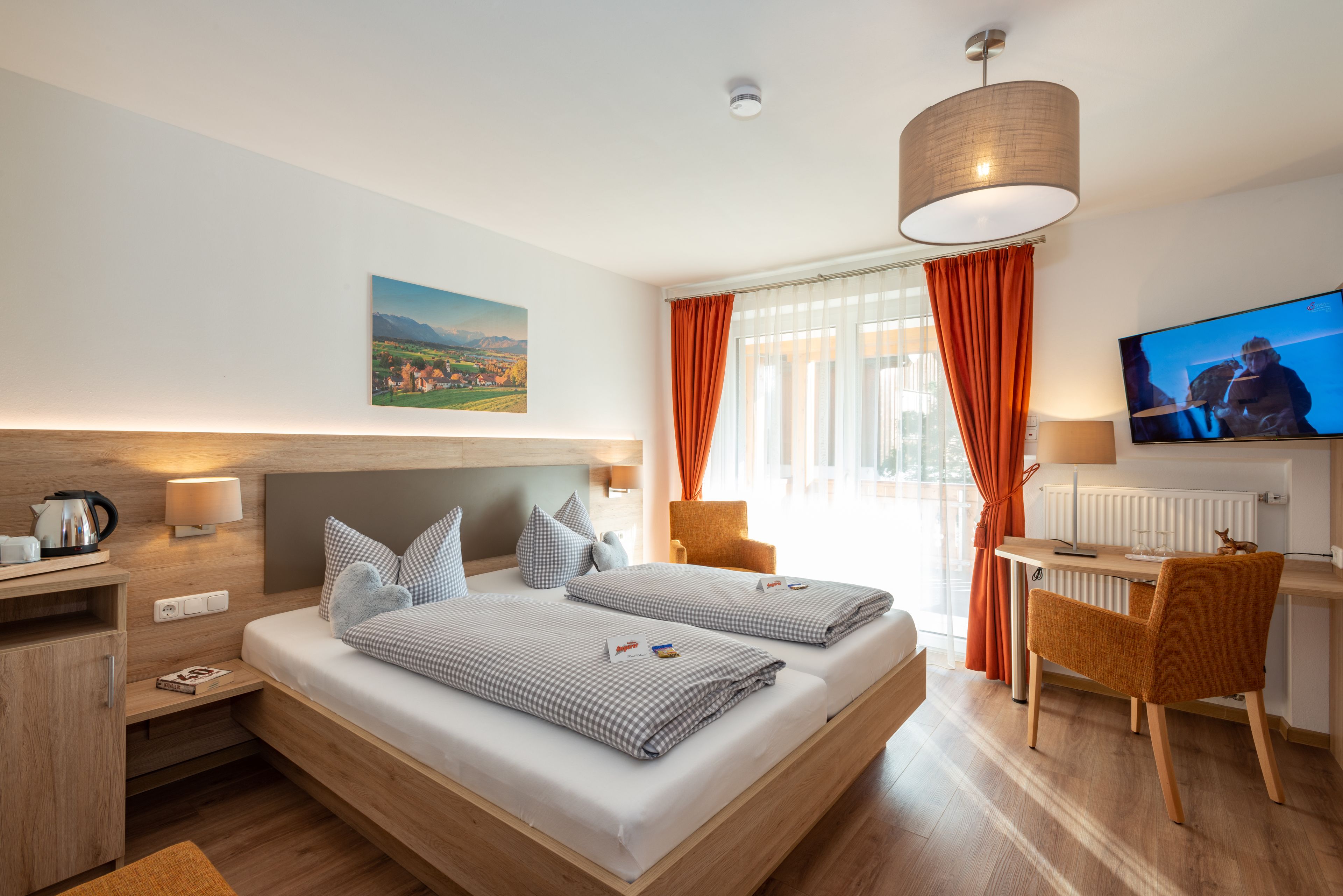 A modern hotel room with a large bed, a desk, a chair, a TV, and a painting on the wall.