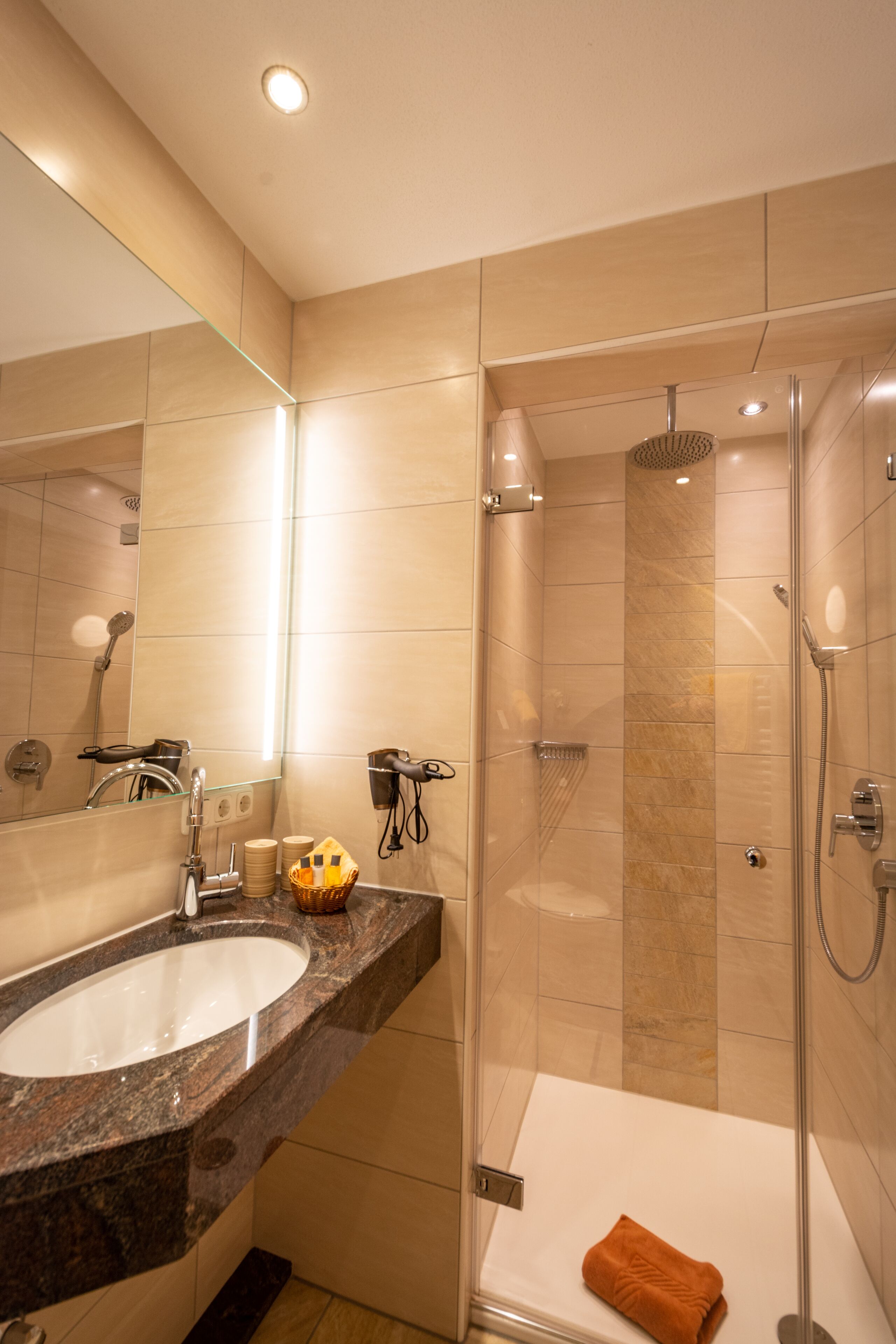 A modern bathroom with a sink, mirror, and shower.