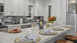 Une cuisine moderne avec des meubles blancs, un plan de travail en marbre et un îlot central doté de tabourets.
