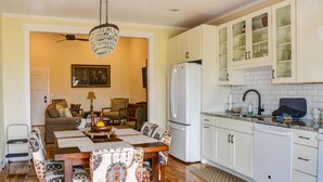Una cocina compacta con gabinetes blancos, un refrigerador y una zona de comedor con mesa y sillas.