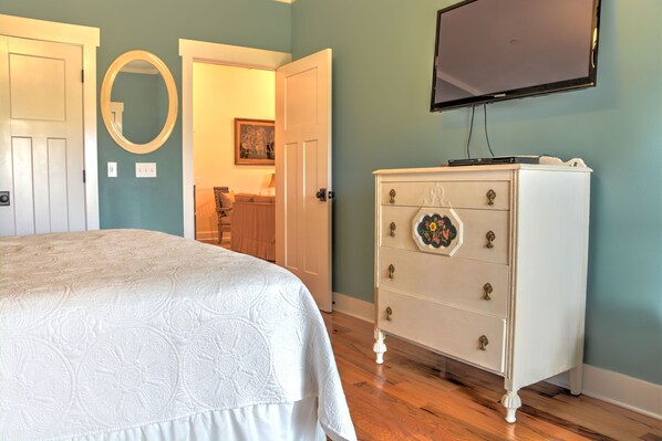 Ein Schlafzimmer mit Bett, Kommode und Fernseher an der Wand.