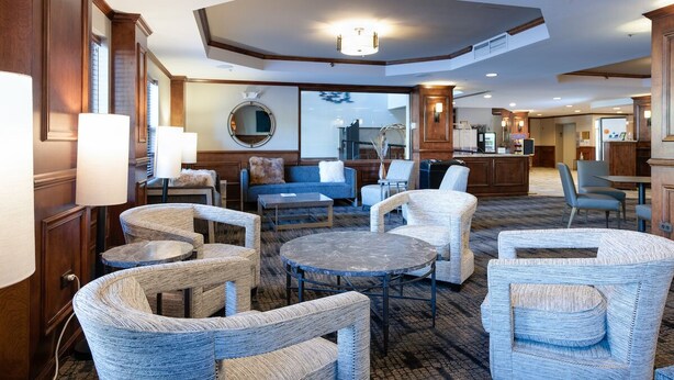 A hotel lobby with round tables, wicker chairs, a blue sofa, and wooden cabinetry. - River Mountain Lodge Colorado Trail Condo: Ski-In, Downtown Breck (Breckenridge)