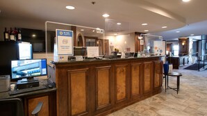 A reception area with a wooden counter, a computer monitor, a sign indicating debit/credit card acceptance, and a television displaying a hotel website. - River Mountain Lodge Colorado Trail Condo: Ski-In, Downtown Breck (Breckenridge)