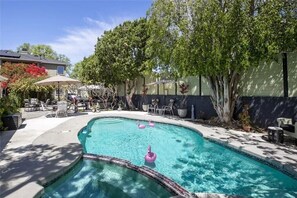 Relax by the pool surrounded by lush greenery and comfortable outdoor seating.