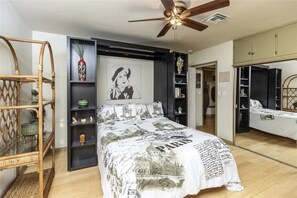 Relax in this stylish bedroom with a central bed, wicker chair, and shelving unit.