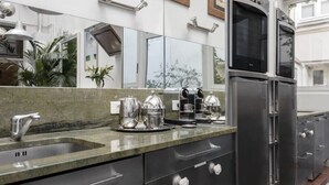 Una cocina moderna con electrodomésticos de acero inoxidable, encimera de granito y un espejo grande sobre el lavadero.