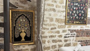 Una habitación con pared de piedra, cama, silla y una obra de arte enmarcada.