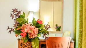 A round table with a copper base and a woven basket containing pink and purple flowers. - Tchero Hotel (Douala)