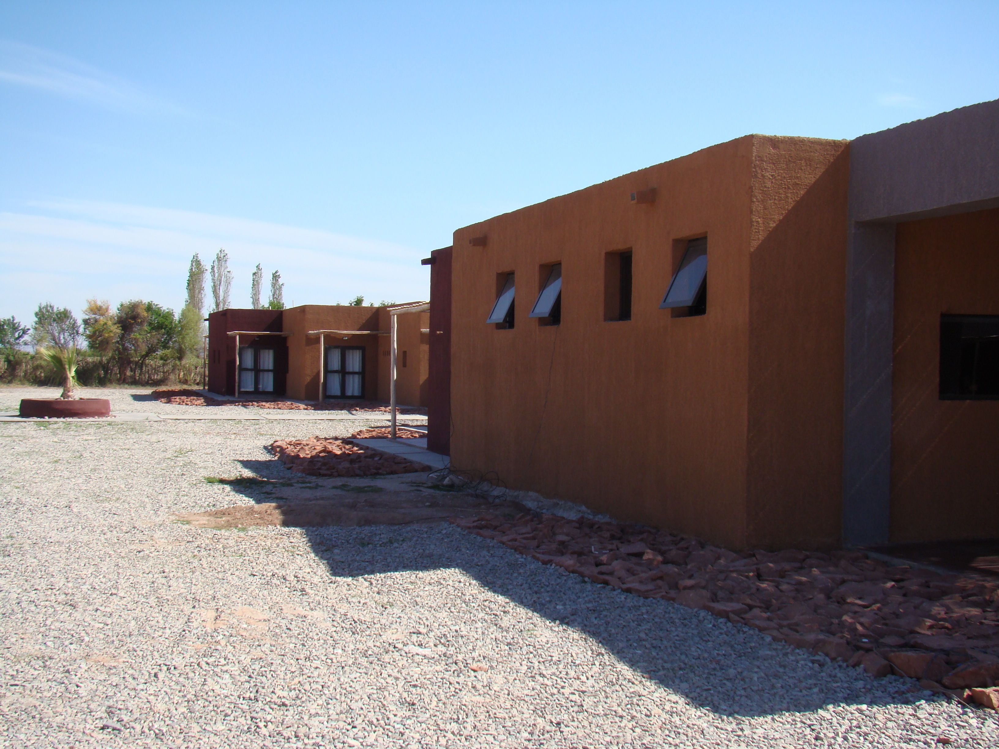 A building with a modern design, featuring a gravel driveway and a small garden area.