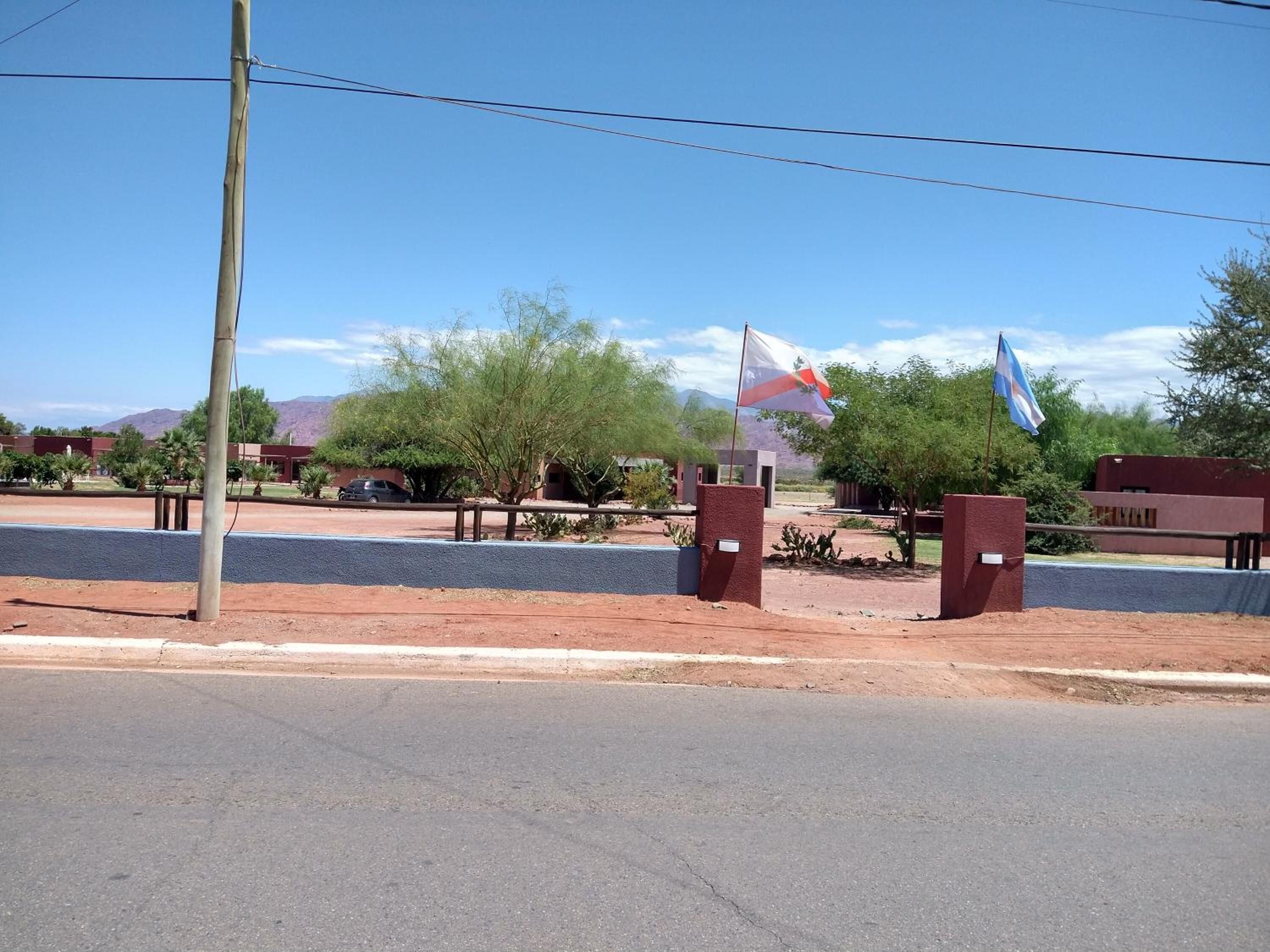 A parking lot with a flagpole, a building, and a clear sky.