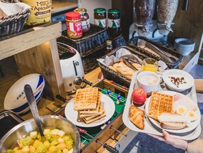 Un bufé de desayuno con gofres, tostadas, fruta y diversas opciones para untar.