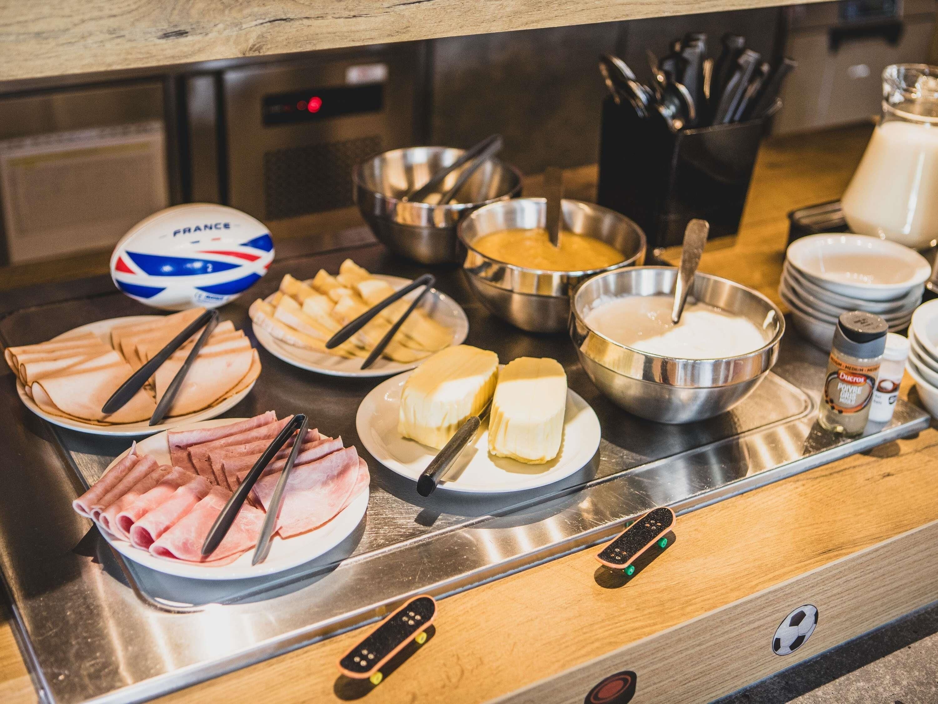 Una mesa de buffet con diferentes opciones de comida, incluyendo carnes, quesos y un tazón de sopa.