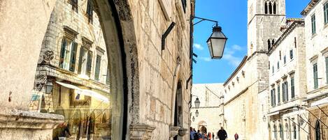 Una calle histórica con edificios de piedra, una torre destacada y un escaparate lleno de libros.