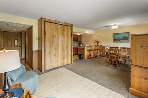 A compact living space with a kitchenette, dining area, and a door leading to another room.