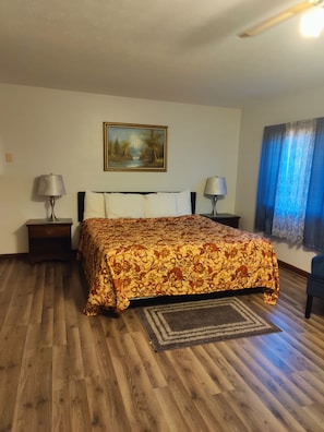 A bedroom with a bed, two nightstands, a painting on the wall, and a window with curtains. - Hotel Nashville (Nashville)
