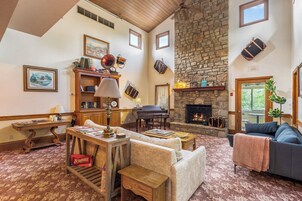 A cozy living room with a fireplace, a piano, and a stone wall.