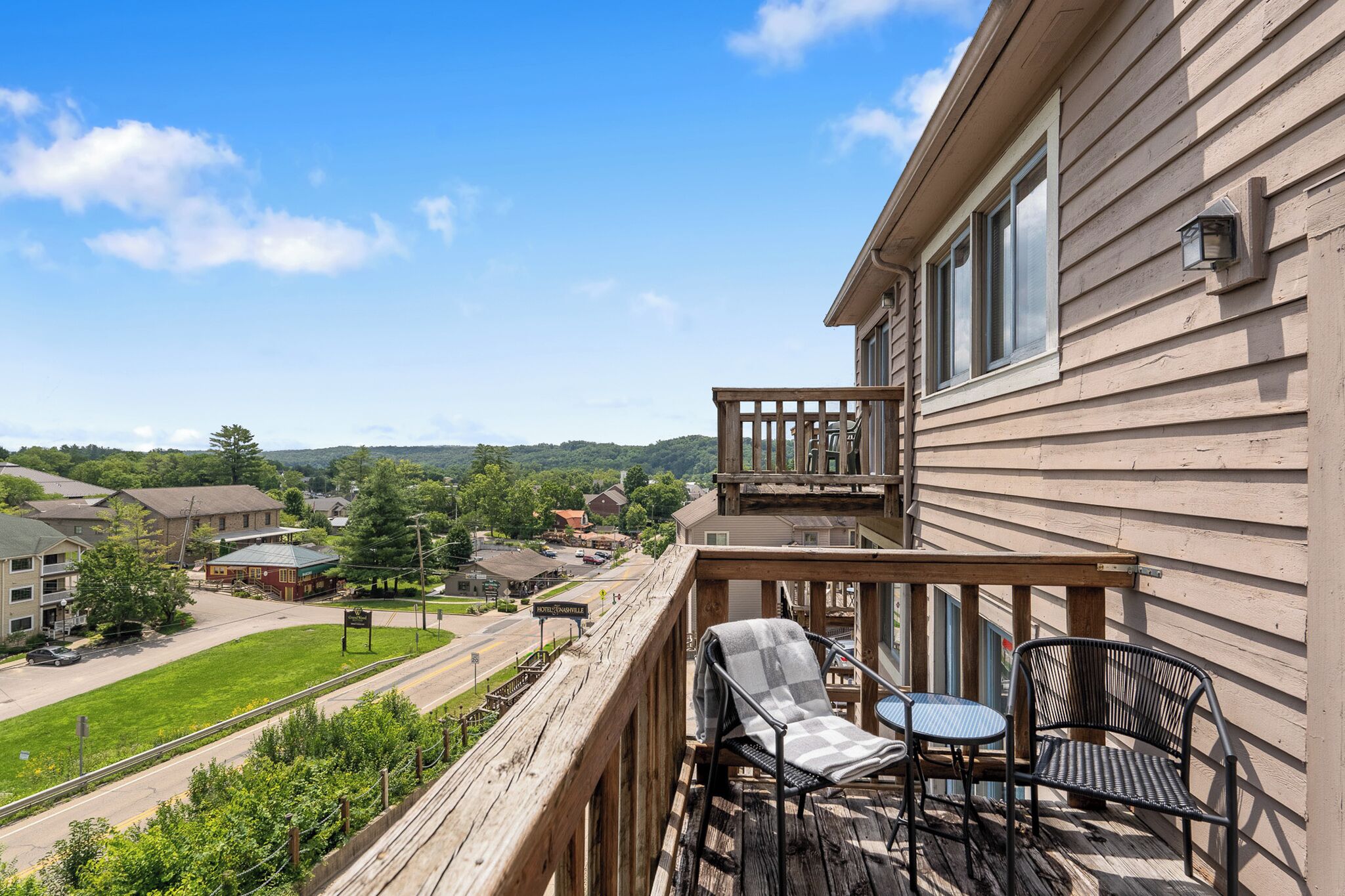 Ein Balkon mit Gartenmöbeln, Blick auf eine Stadt und ein Hotelschild.