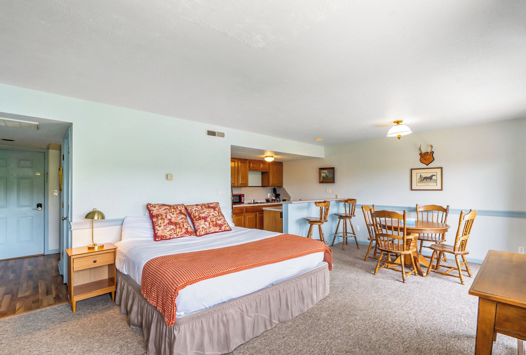 A bedroom with a bed, a desk, and a chair. There is a door and a window.
