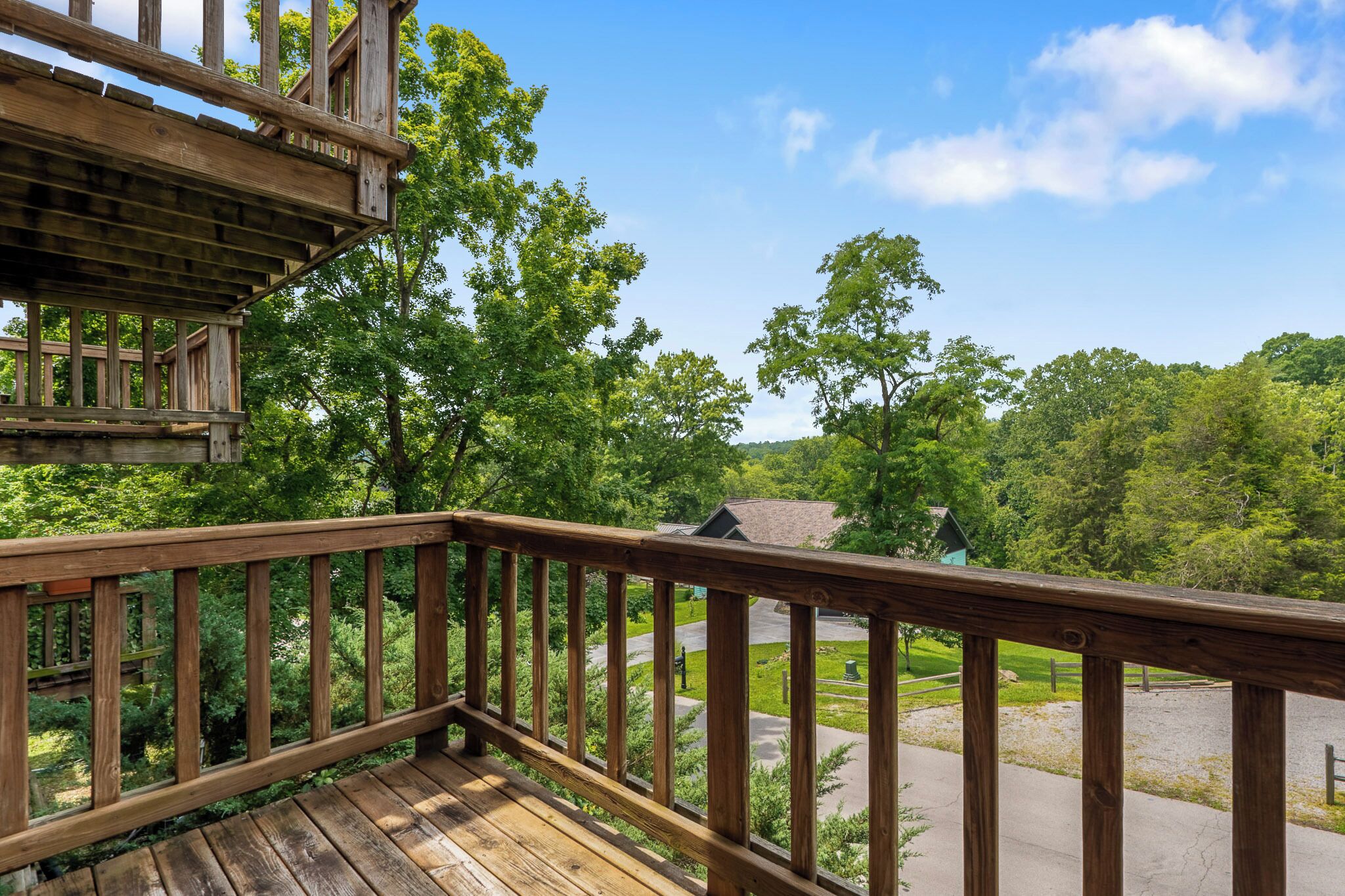 A wooden deck with a view of a forested area and a building in the distance.