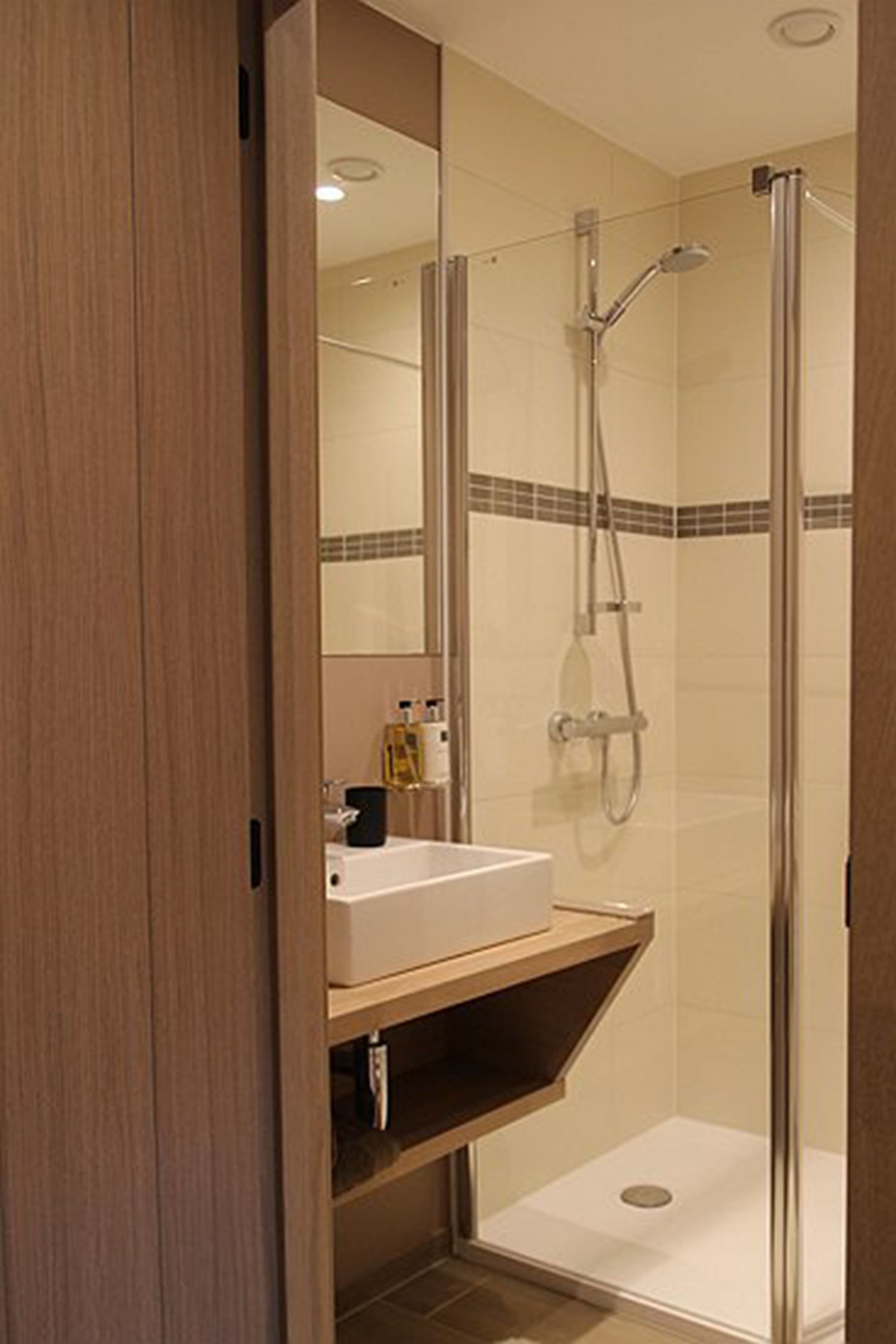 Een moderne badkamer met een douchecabine van glas, een wastafelmeubel en een spiegel.