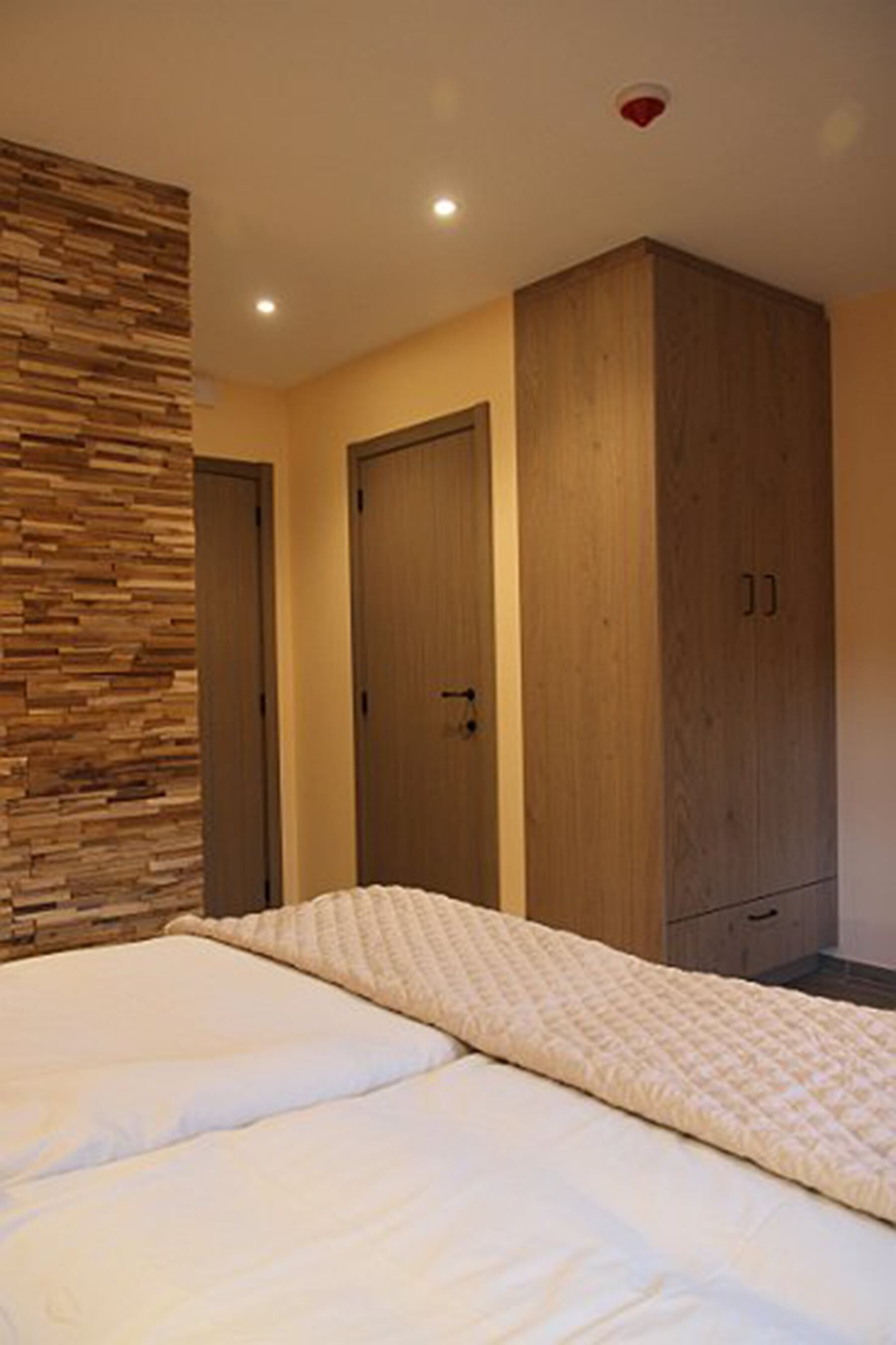 Un dormitorio con cama, armario de madera y una pared con diseño de paneles de madera.