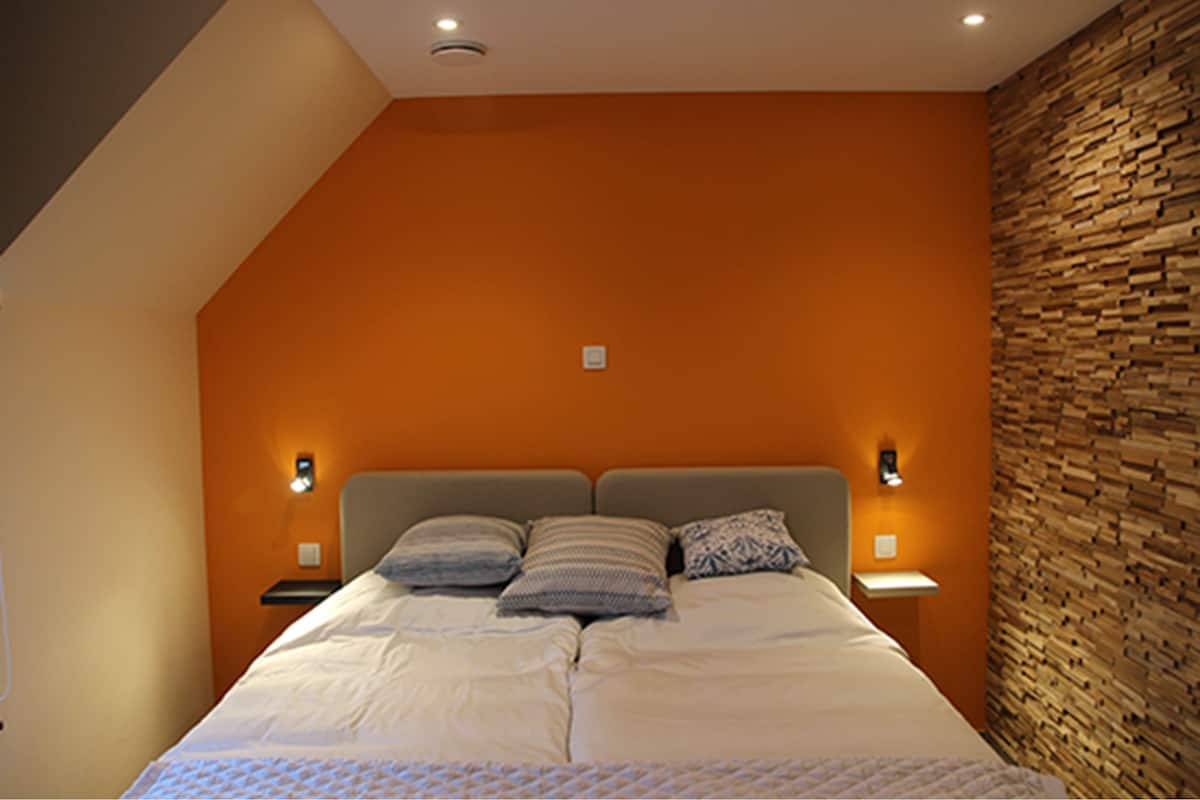 A bedroom with a bed, two bedside tables, and a stone wall.