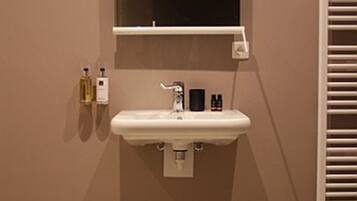 Een badkamer met een witte wastafel, een spiegel en een handdoekhouder.