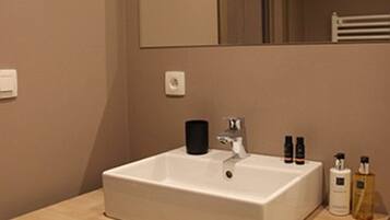 A modern bathroom with a large mirror, a white sink, and a wooden vanity.