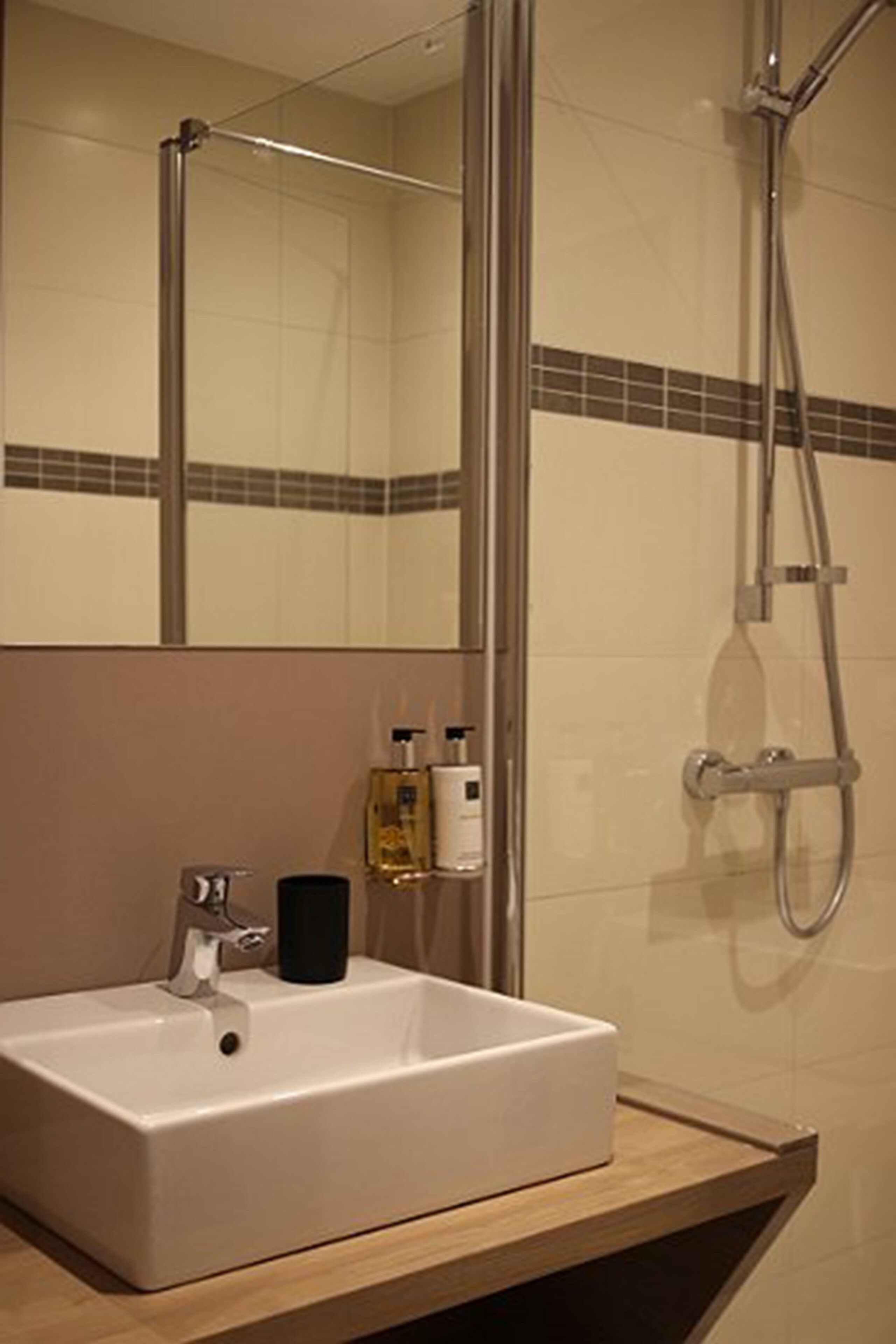 A bathroom with a white sink, a mirror, and a shower.