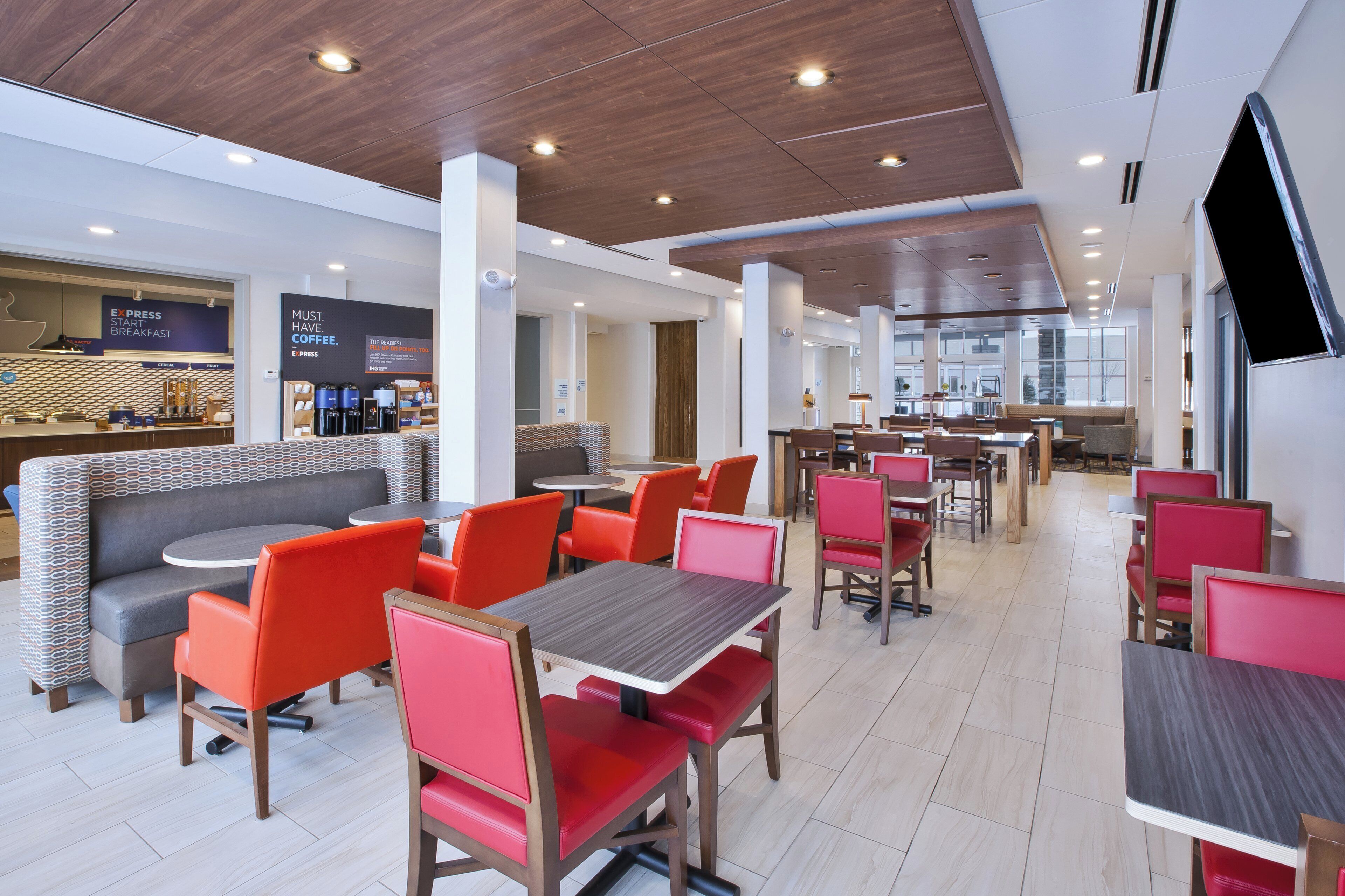 Um hall de hotel moderno com áreas de estar, um café e vista para a cidade.