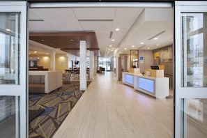 A hotel lobby with a reception desk, seating area, and a carpeted floor. - Holiday Inn Express Auburn Hills South (Auburn Hills)