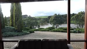 A view from a room with a large window overlooking a landscaped area with trees and a body of water. - Leawarra stays in the farm - Fleurieu Peninsula (Pages Flat)