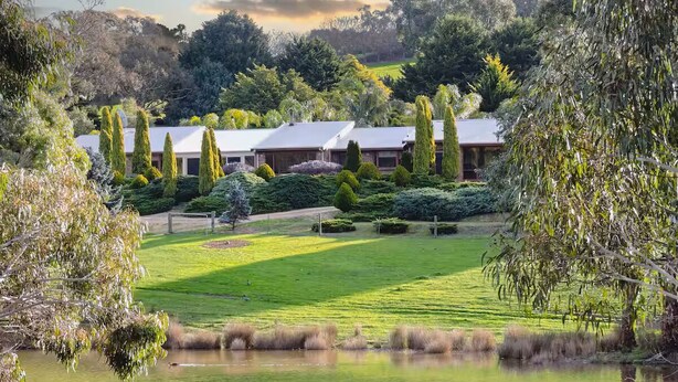 A serene landscape with a pond, manicured lawn, and a building with a white roof. - Leawarra stays in the farm - Fleurieu Peninsula (Pages Flat)