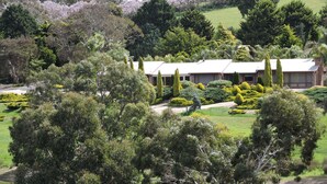 A building with a symmetrical facade, surrounded by well-maintained gardens and trees. - Leawarra stays in the farm - Fleurieu Peninsula (Pages Flat)