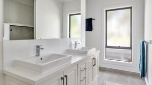 A modern bathroom with a double sink vanity, a large mirror, and a frosted window. - Diamond Bay Beach House (SORRENTO)
