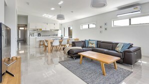 A modern living room with a sofa, coffee table, and dining area. - Diamond Bay Beach House (SORRENTO)