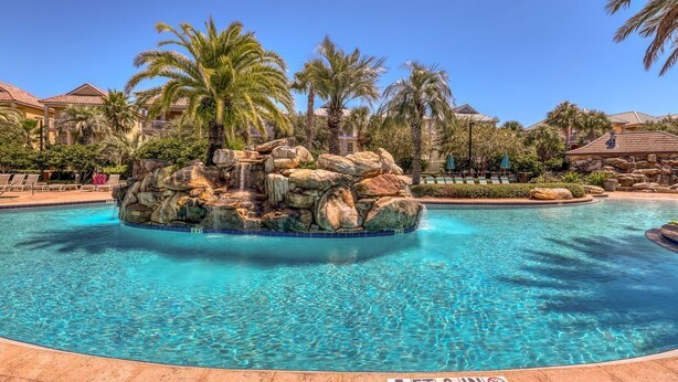 A pool with a rock feature and palm trees. - 🏝️ Seaside Therapy| 6BR | Near Resort Pool and Beach! (Destin)