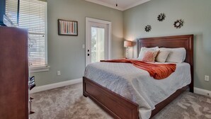 A bedroom with a large bed, a ceiling fan, and a door with a window.