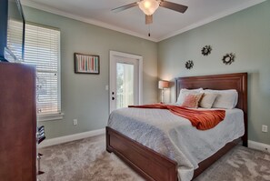 Une chambre avec un grand lit, un ventilateur de plafond et une porte avec une fenêtre.