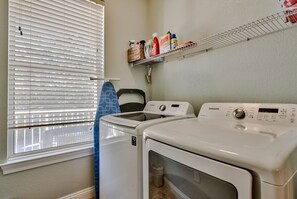 A laundry room with a washing machine, dryer, and a shelf with cleaning supplies. - 🏝️ Seaside Therapy| 6BR | Near Resort Pool and Beach! (Destin)