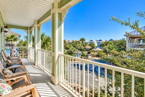 A covered balcony with wooden chairs and a view of a resort area. - 🏝️ Seaside Therapy| 6BR | Near Resort Pool and Beach! (Destin)