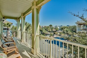 A covered balcony with lounge chairs, a pool, and a view of other buildings and trees. - Seaside Therapy | Only 100ft to Resort-Style Pool and Short Walk to the Beach (Destin)