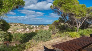 Un banc en bois donnant sur une plage, avec un ciel dégagé.