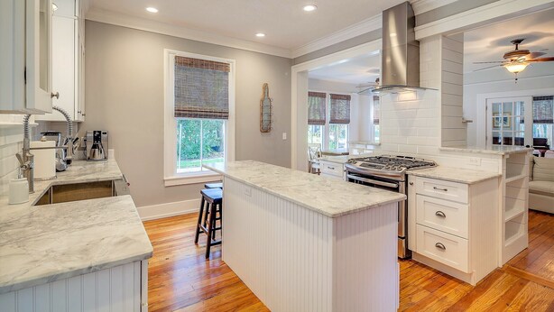 A kitchen with white cabinetry, a marble countertop, and a built-in stove.